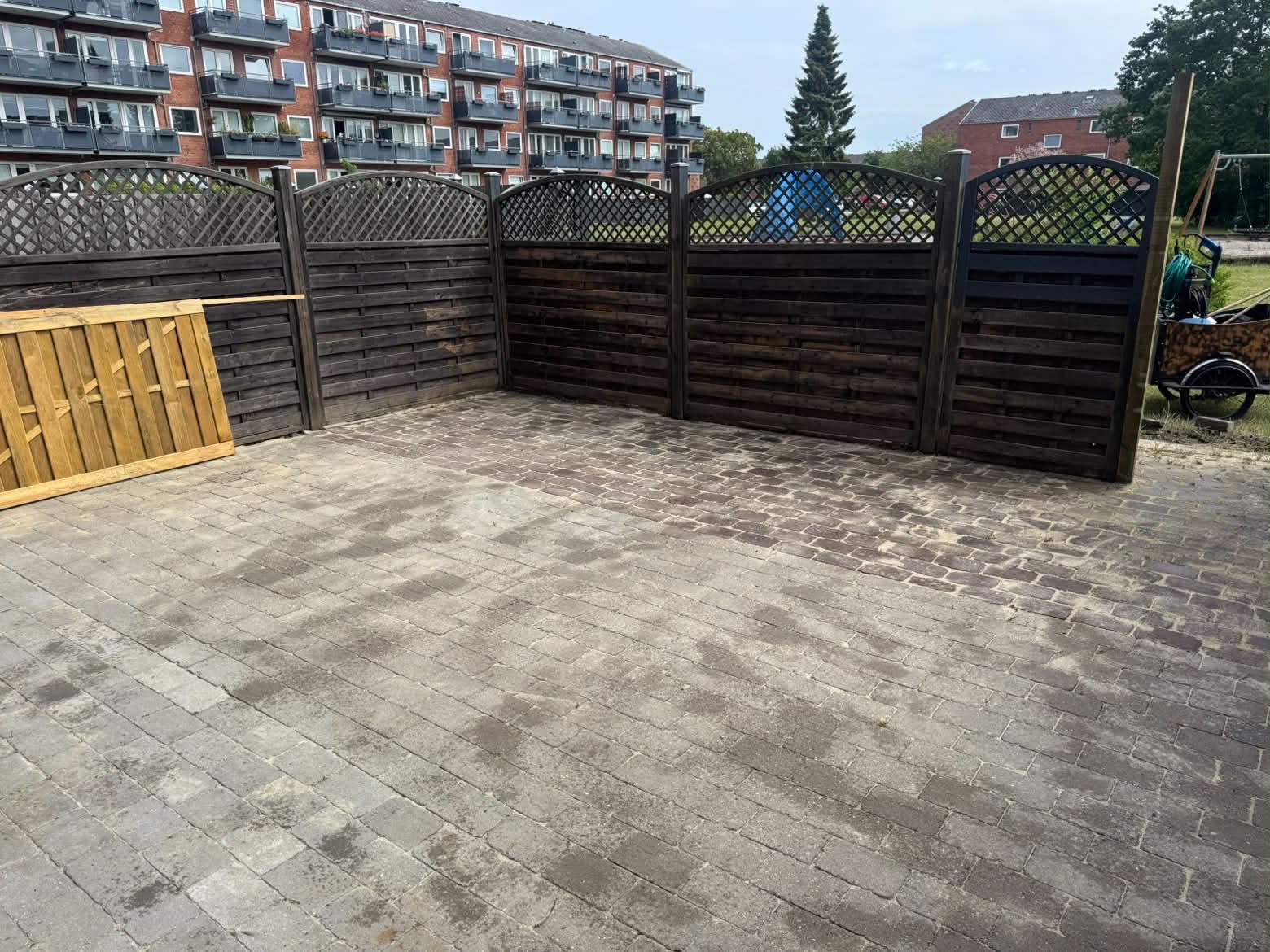 Fliseterrasse og hegn ved et boligområde.